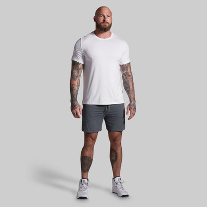 Man wearing a white t-shirt and gray shorts on a plain background