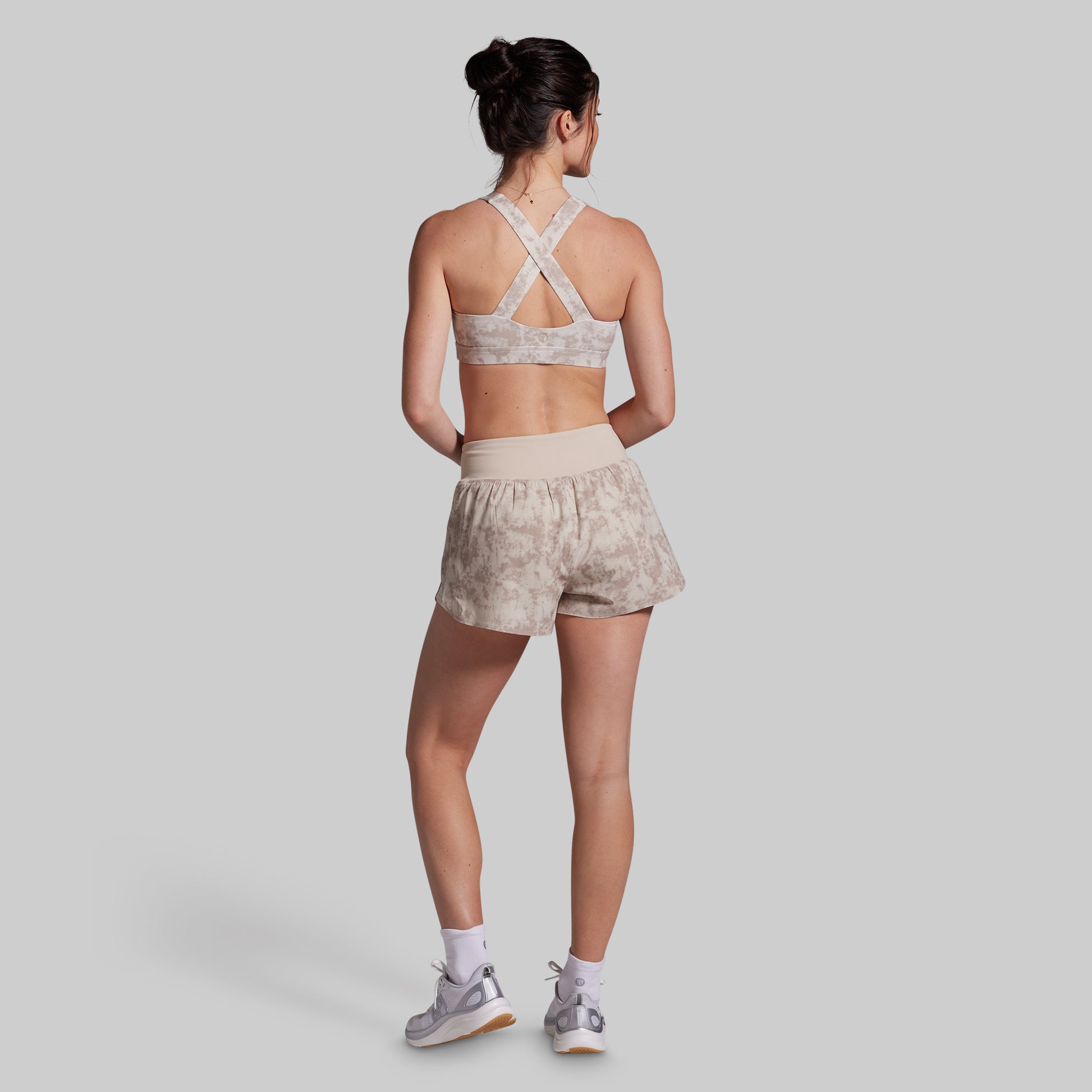 Woman wearing a sports bra and shorts set on a plain background
