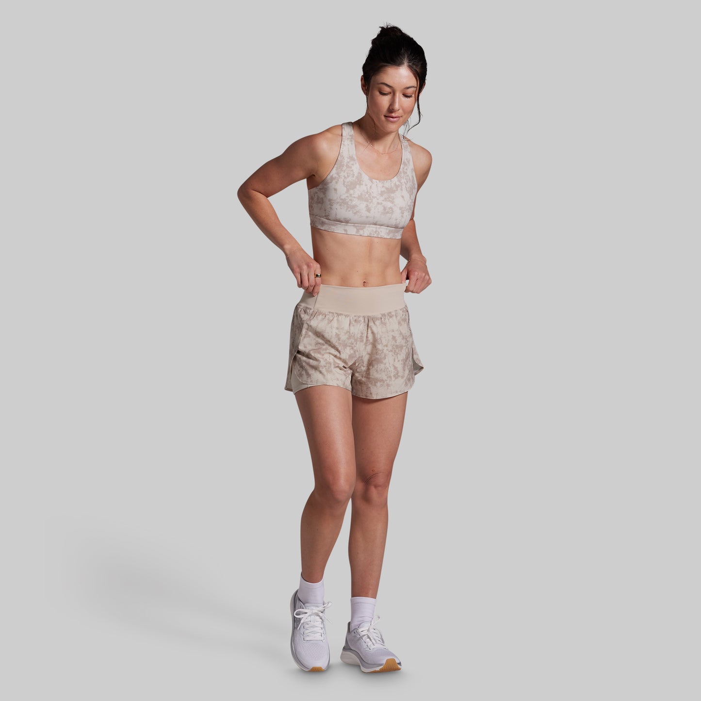 Woman wearing a sports bra and shorts on a plain background