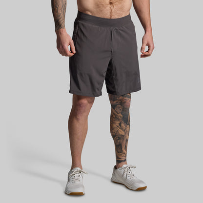 Person wearing dark gray shorts on a light gray background