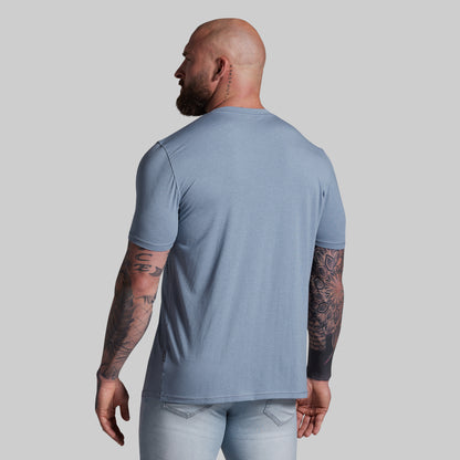 Man wearing a light blue t-shirt and pants on a gray background
