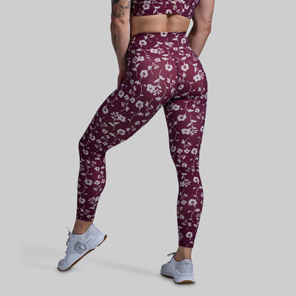 Person wearing maroon leggings with floral pattern on a plain background