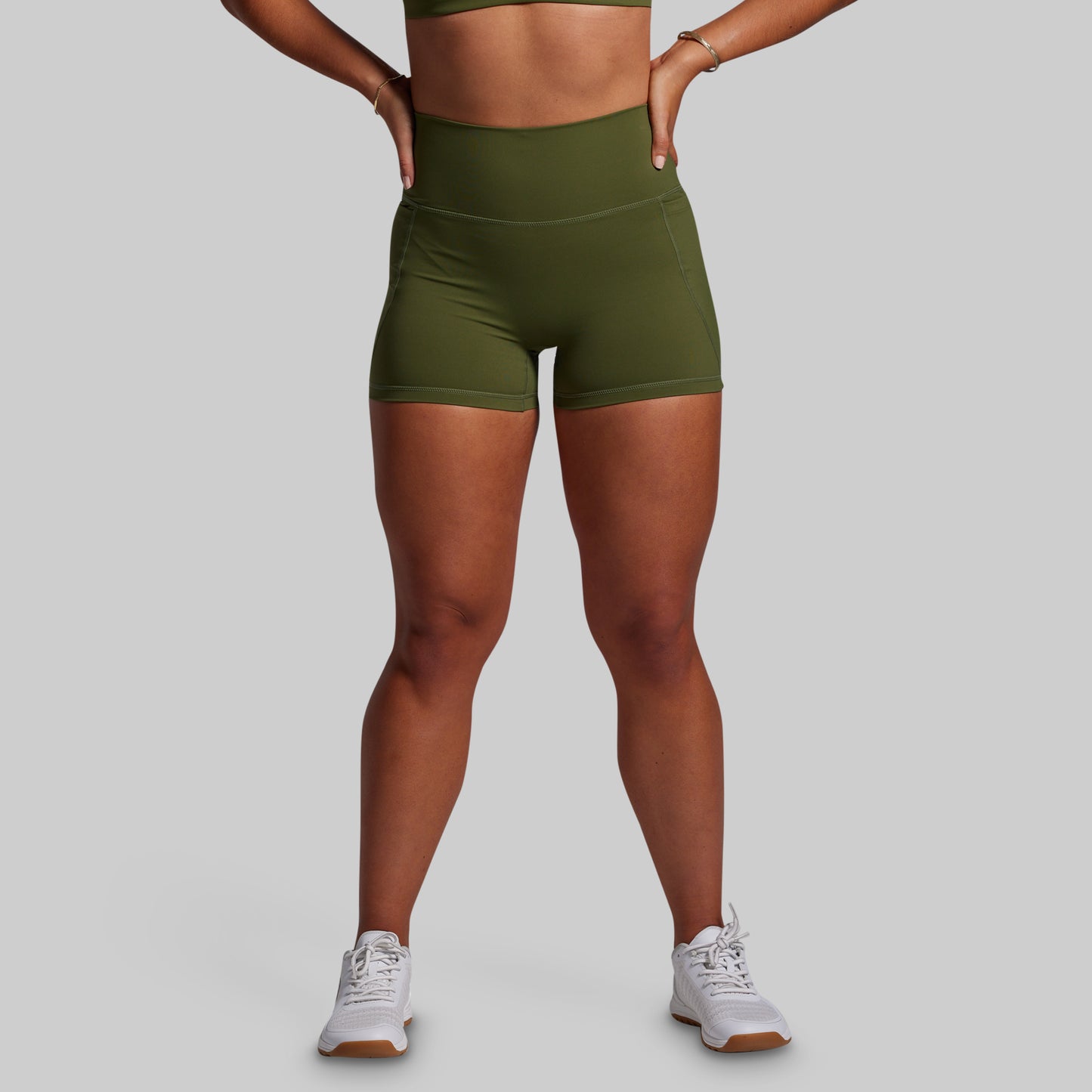 Person wearing green athletic shorts on a gray background