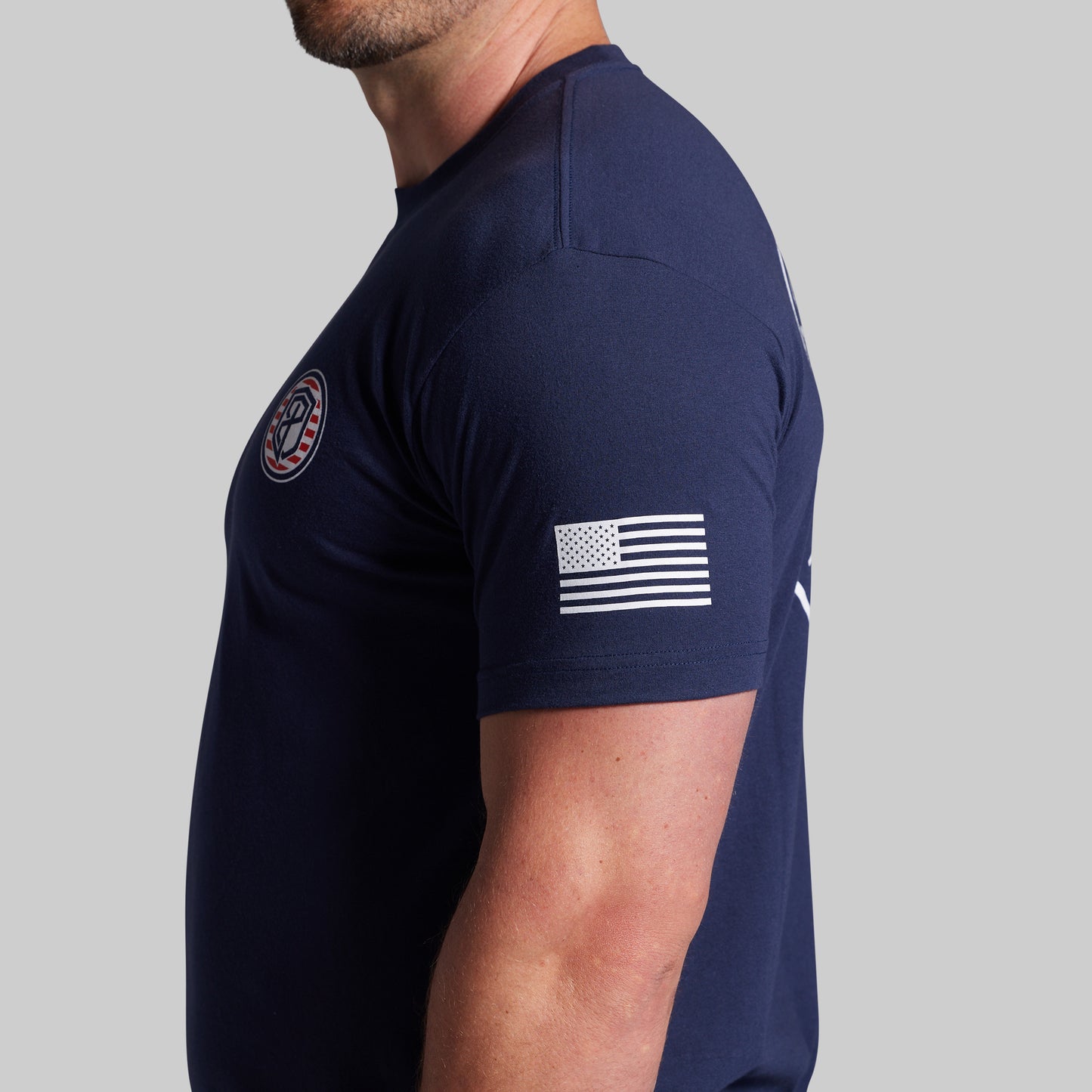 Navy blue t-shirt with American flag design on sleeve against a gray background