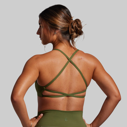 Woman wearing a green sports bra and leggings on a gray background