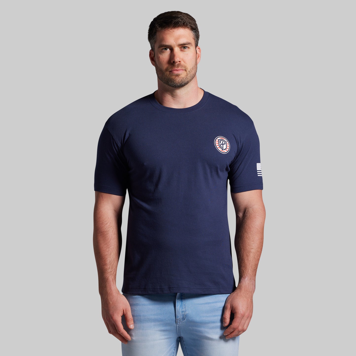 Man wearing a navy blue t-shirt with a logo on a gray background