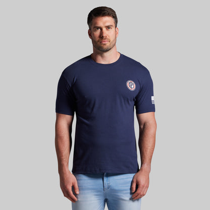 Man wearing a navy blue t-shirt with a logo on a gray background