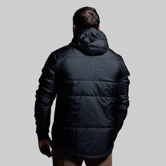 Person wearing a black puffer jacket on a gray background