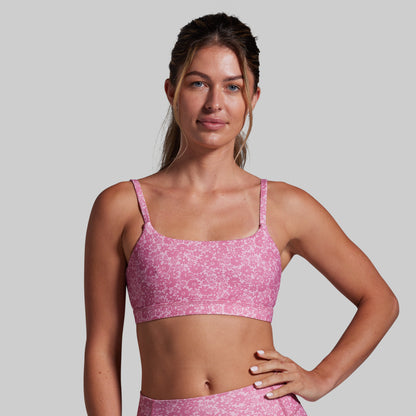 Woman wearing a pink sports bra and leggings against a gray background