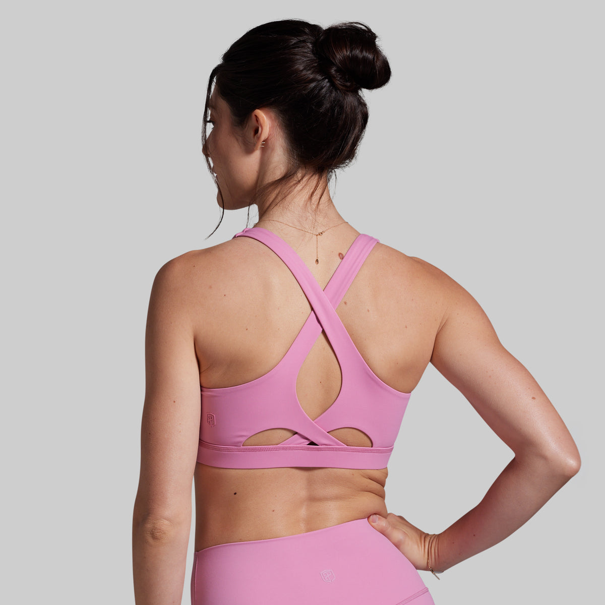 Woman wearing a pink sports bra and leggings on a gray background