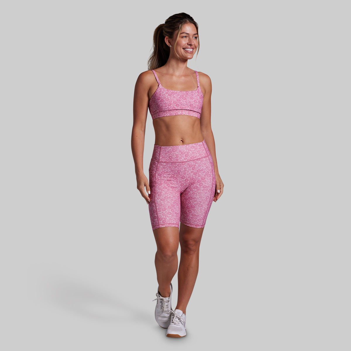 Woman wearing a pink athletic outfit on a gray background