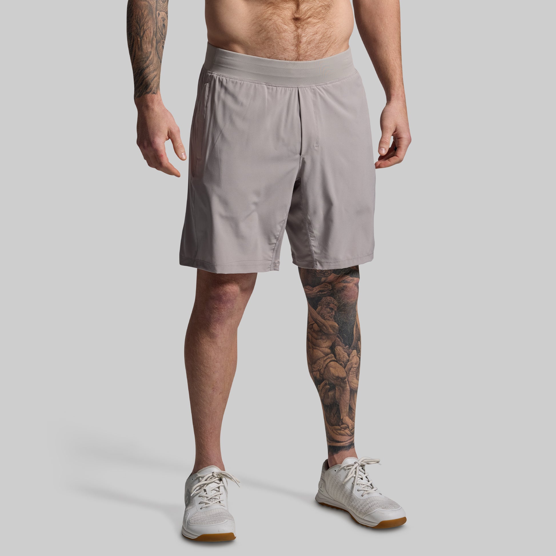 Man wearing light gray shorts on a plain background