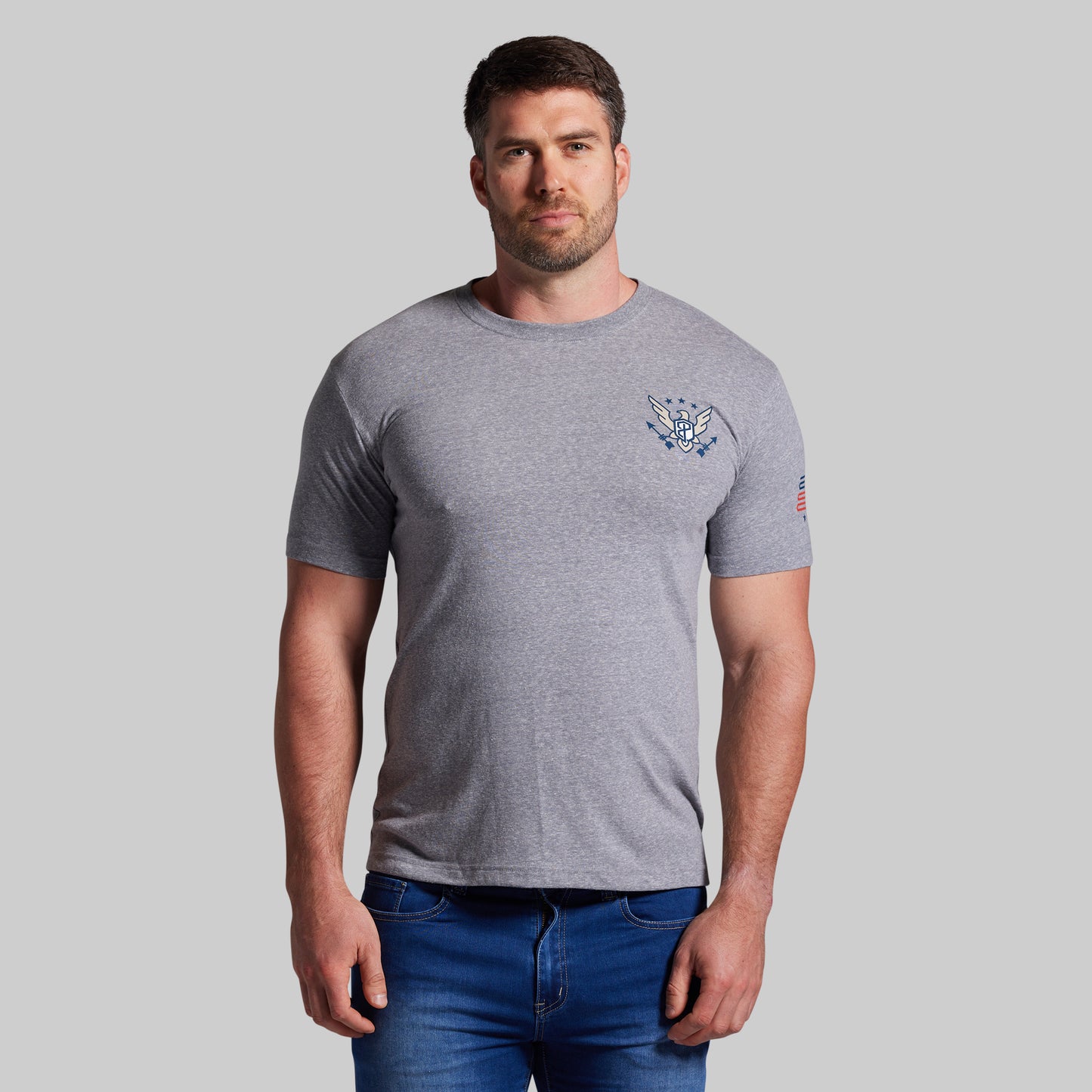 Man wearing a gray t-shirt with a logo on a plain background