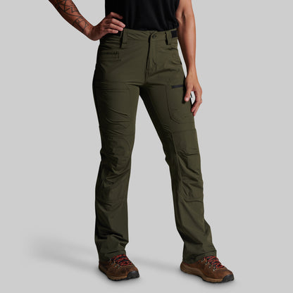 A model wearing olive green technical cargo pants with brown hiking boots, shown from the waist down against a solid gray background.