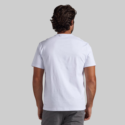 A man viewed from behind wearing a plain white short-sleeve t-shirt and gray pants, set against a solid light gray background.