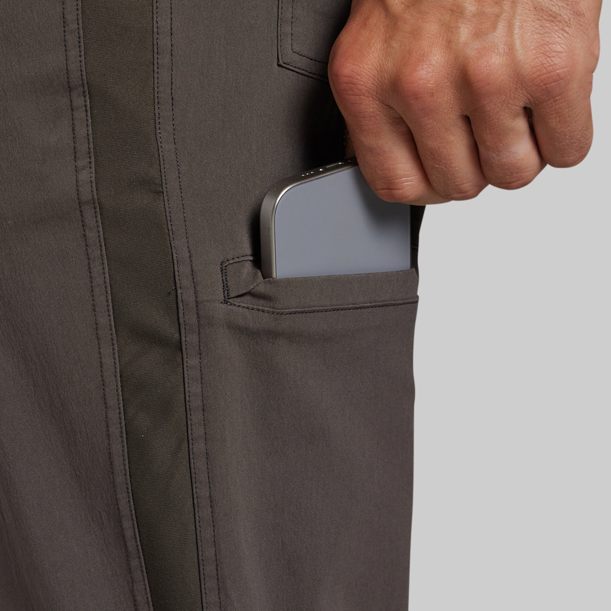 Close-up of a person's hand pulling a silver smartphone out of a side pocket of dark gray utility pants.