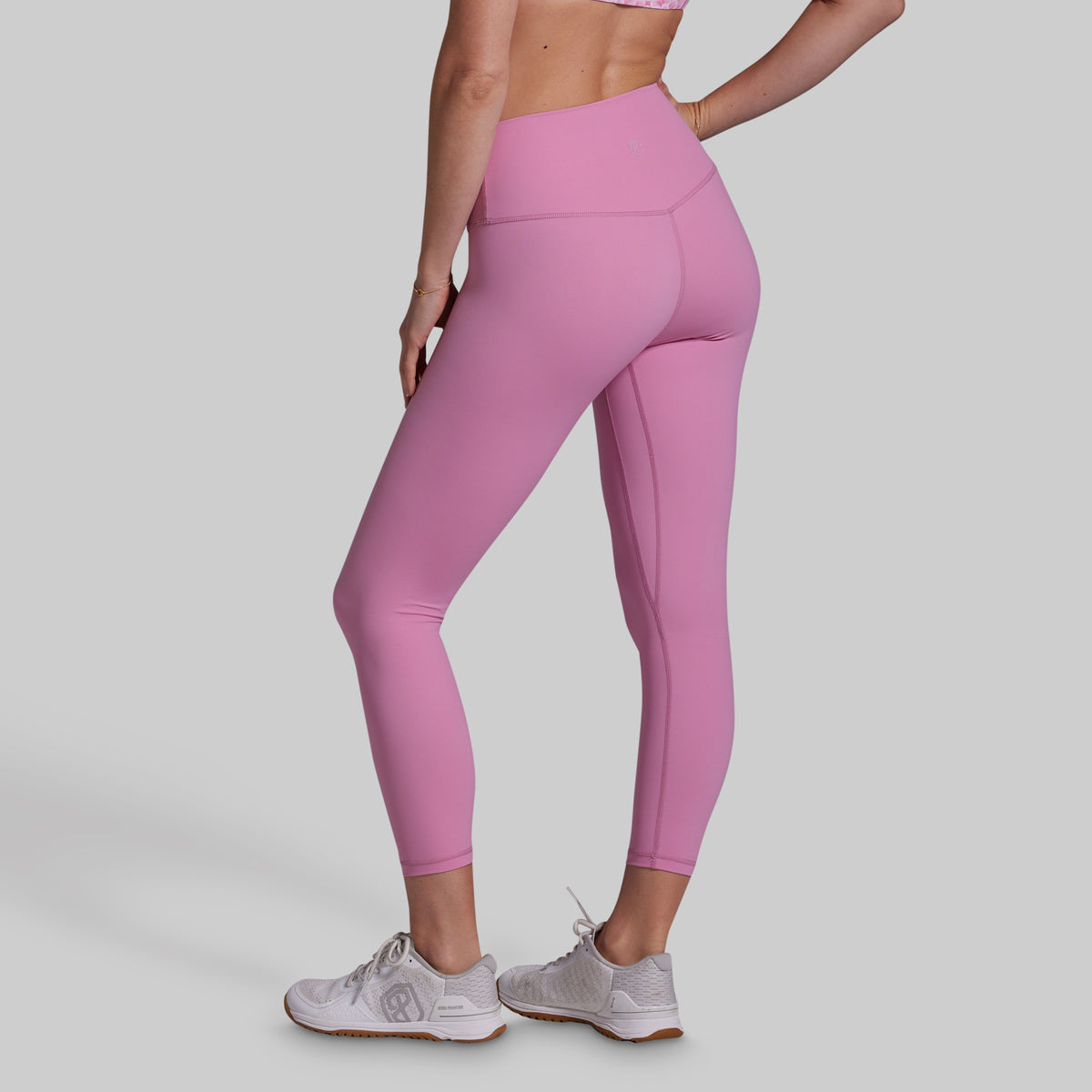 Person wearing pink leggings on a plain background