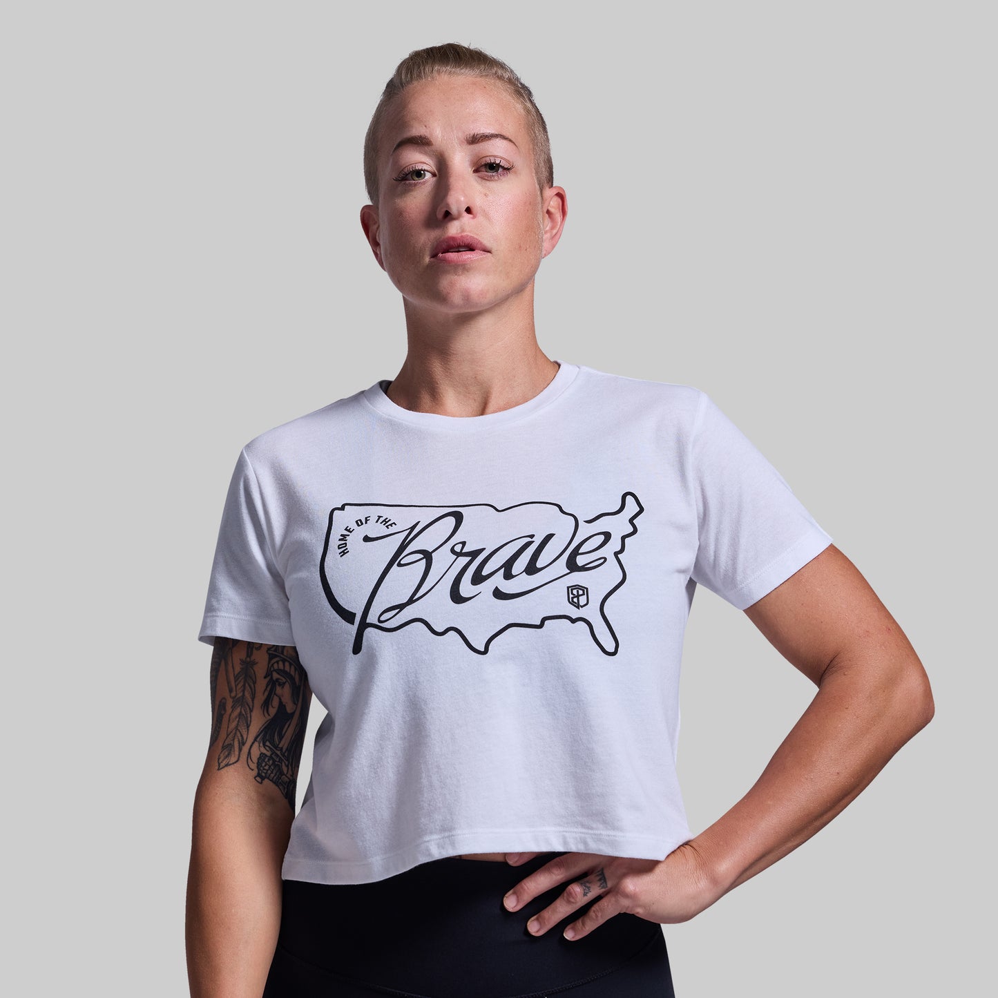Person wearing a white t-shirt with 'Home of the Brave' design on a plain background