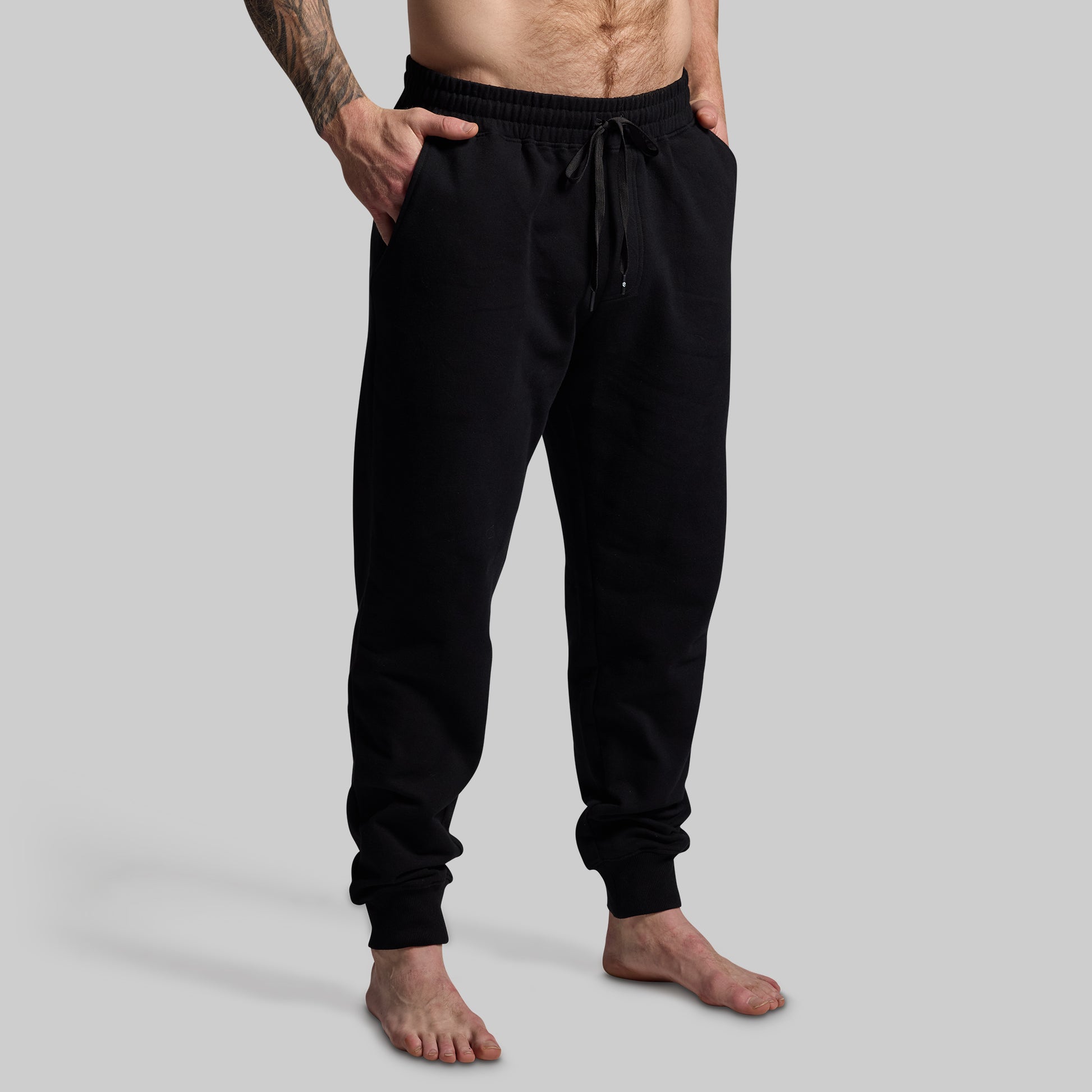 Person wearing black jogger pants on a gray background