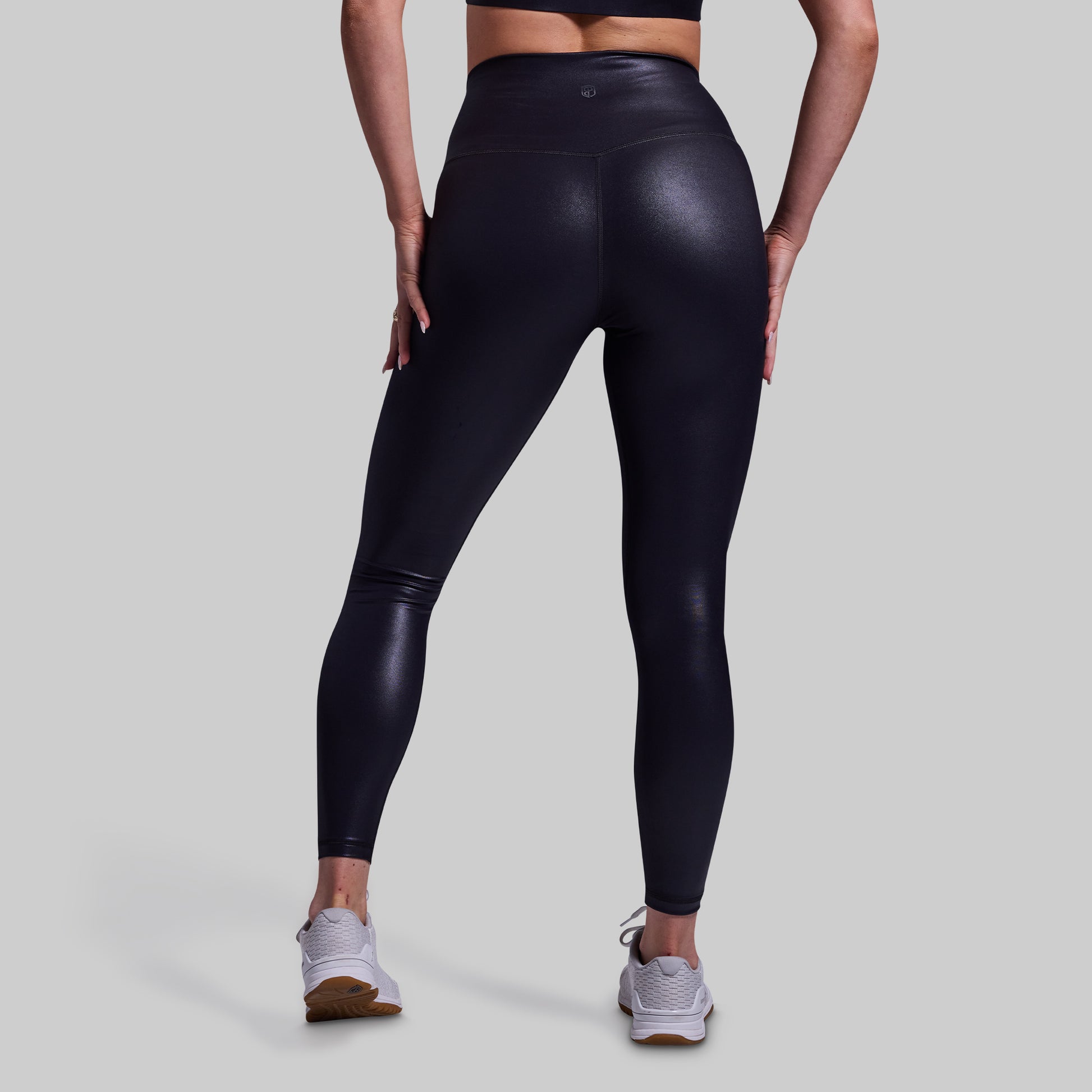 Person wearing black leggings on a light gray background