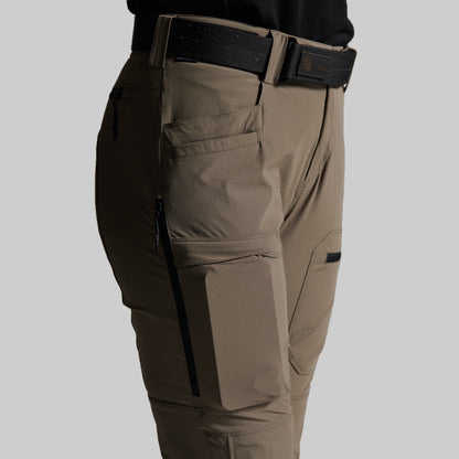 Close-up side view of storm grey cargo pants worn with a black belt, showing side pockets, zippered cargo pockets, and a black waistband on a light gray background.