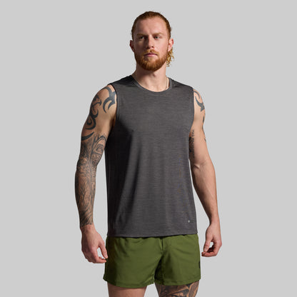 Man wearing a gray sleeveless shirt and green shorts on a gray background