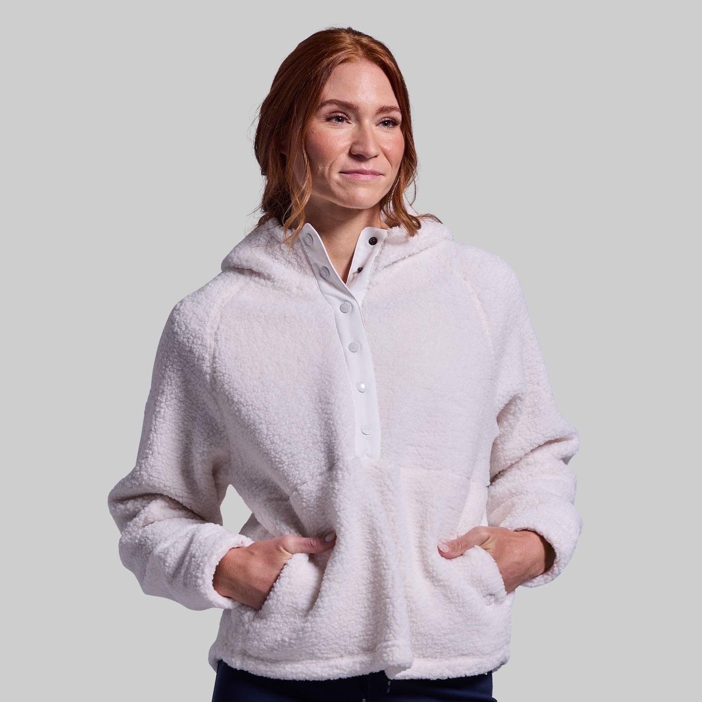 Woman wearing a white fleece jacket against a plain background