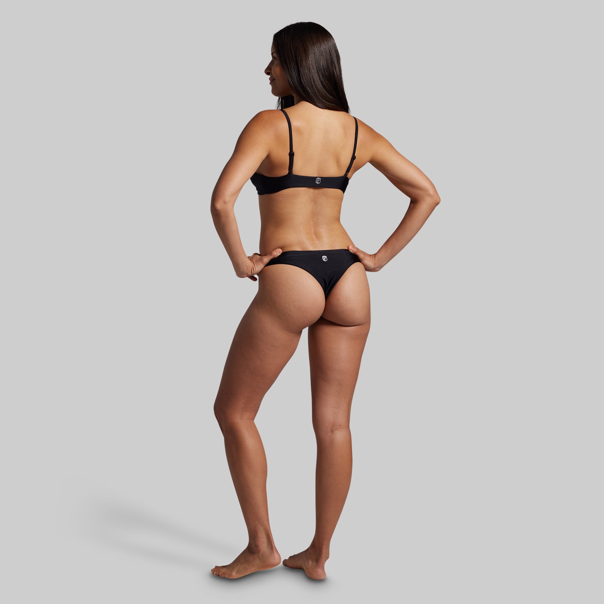 Woman wearing a black bikini on a gray background