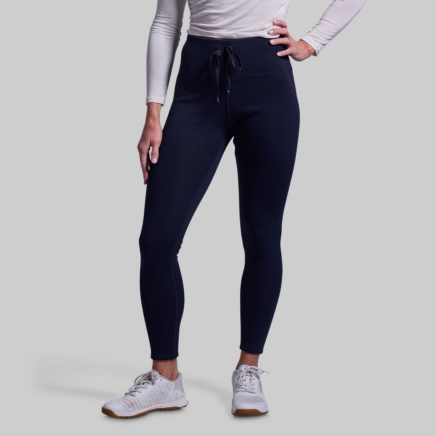 Person wearing navy leggings with a plain background