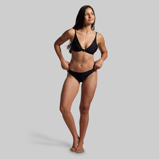Woman wearing a black bikini against a gray background