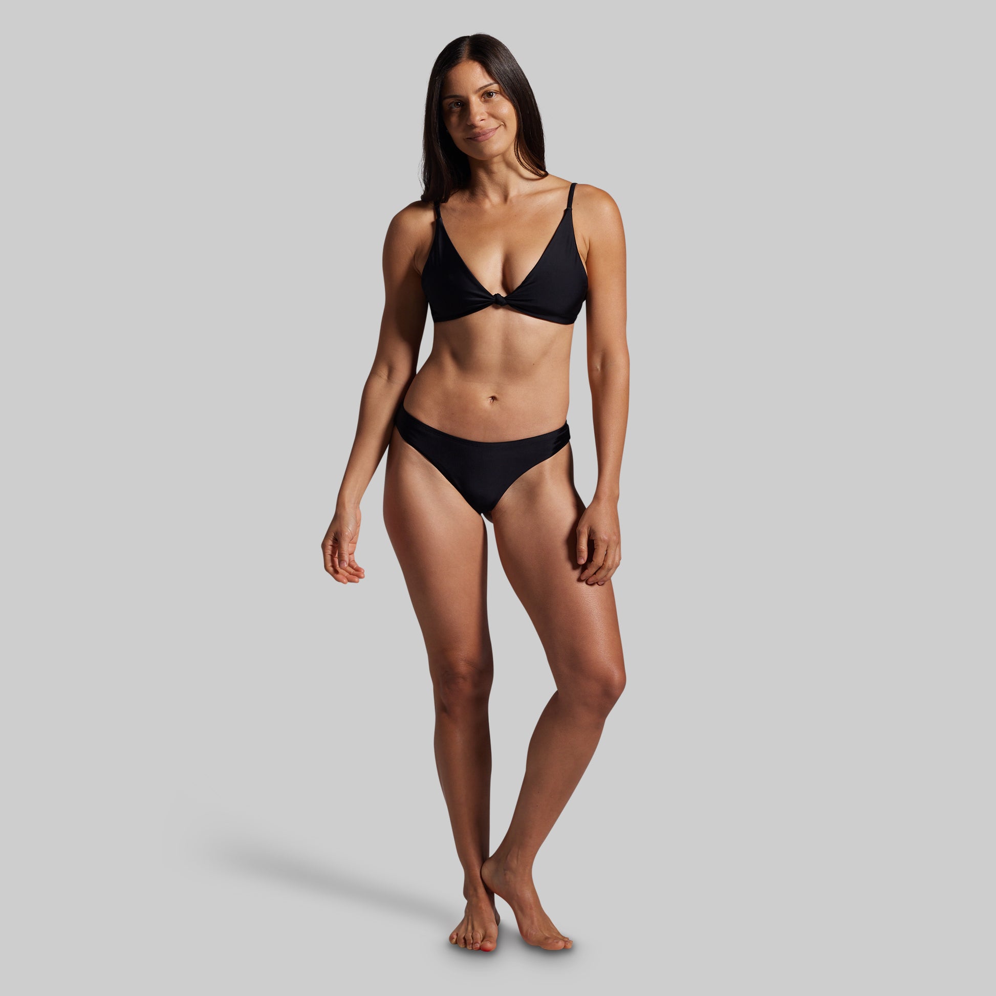 Woman wearing a black bikini against a gray background