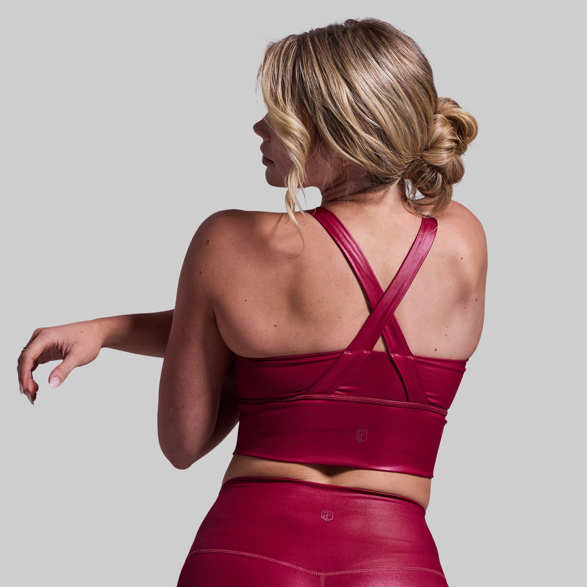 Woman wearing a red sports bra and leggings on a gray background