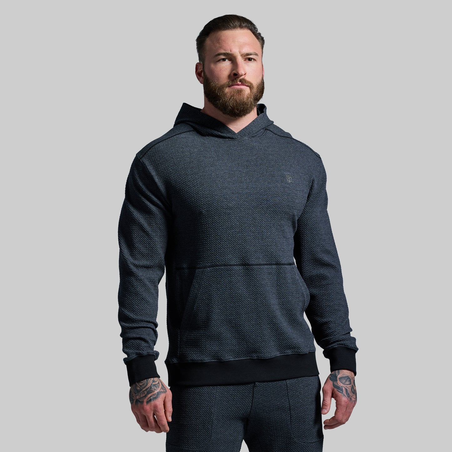 Man wearing a dark gray hoodie on a gray background