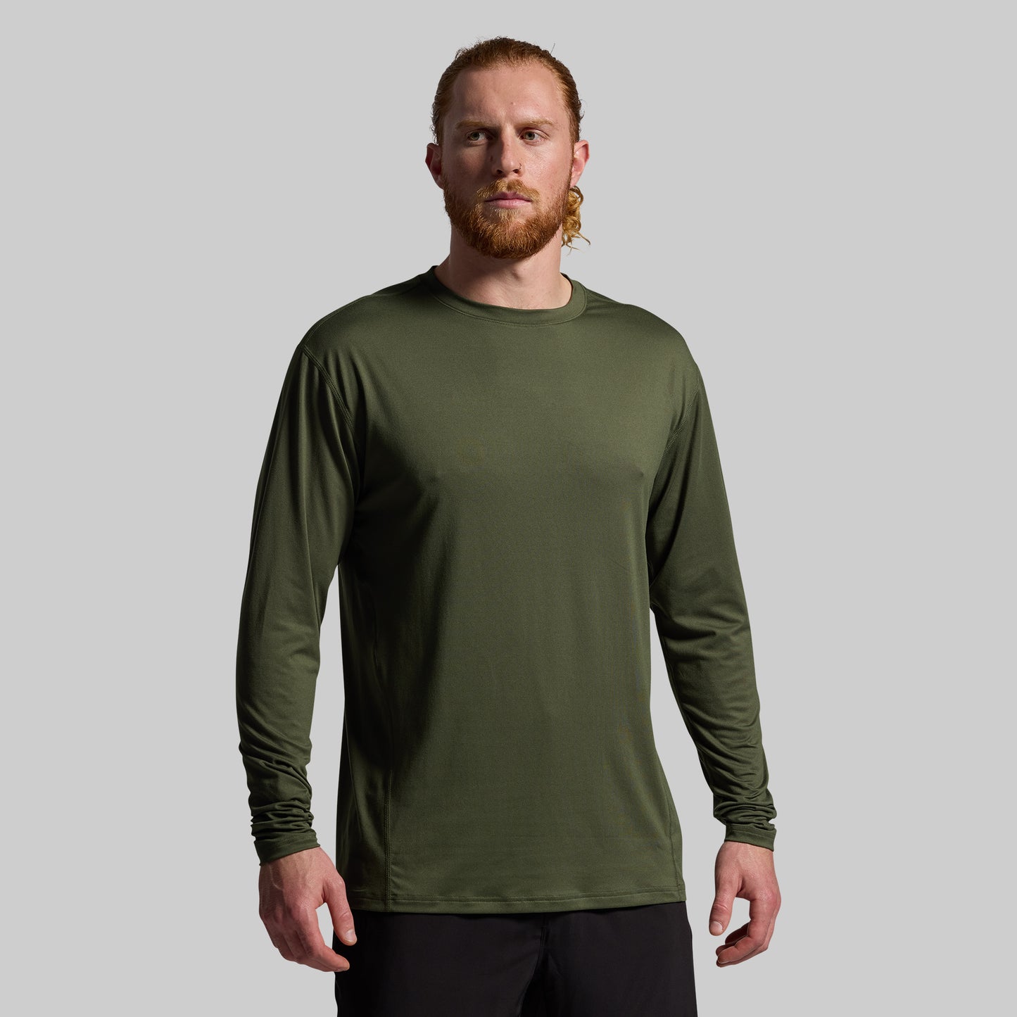 Man wearing a green long-sleeve shirt against a gray background