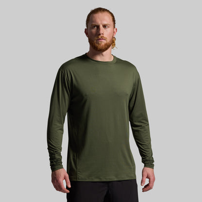 Man wearing a green long-sleeve shirt against a gray background