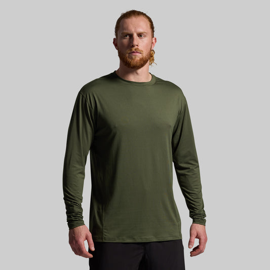 Man wearing a green long-sleeve shirt against a gray background