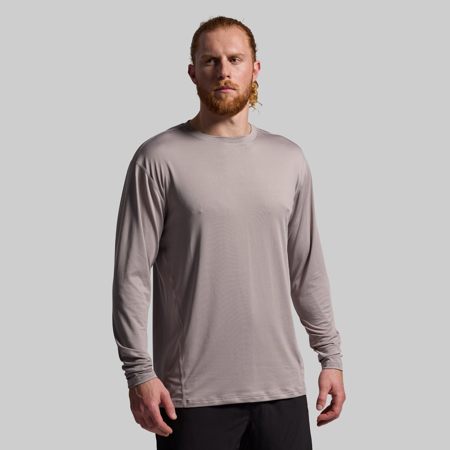 Man wearing a beige long-sleeve shirt against a plain background