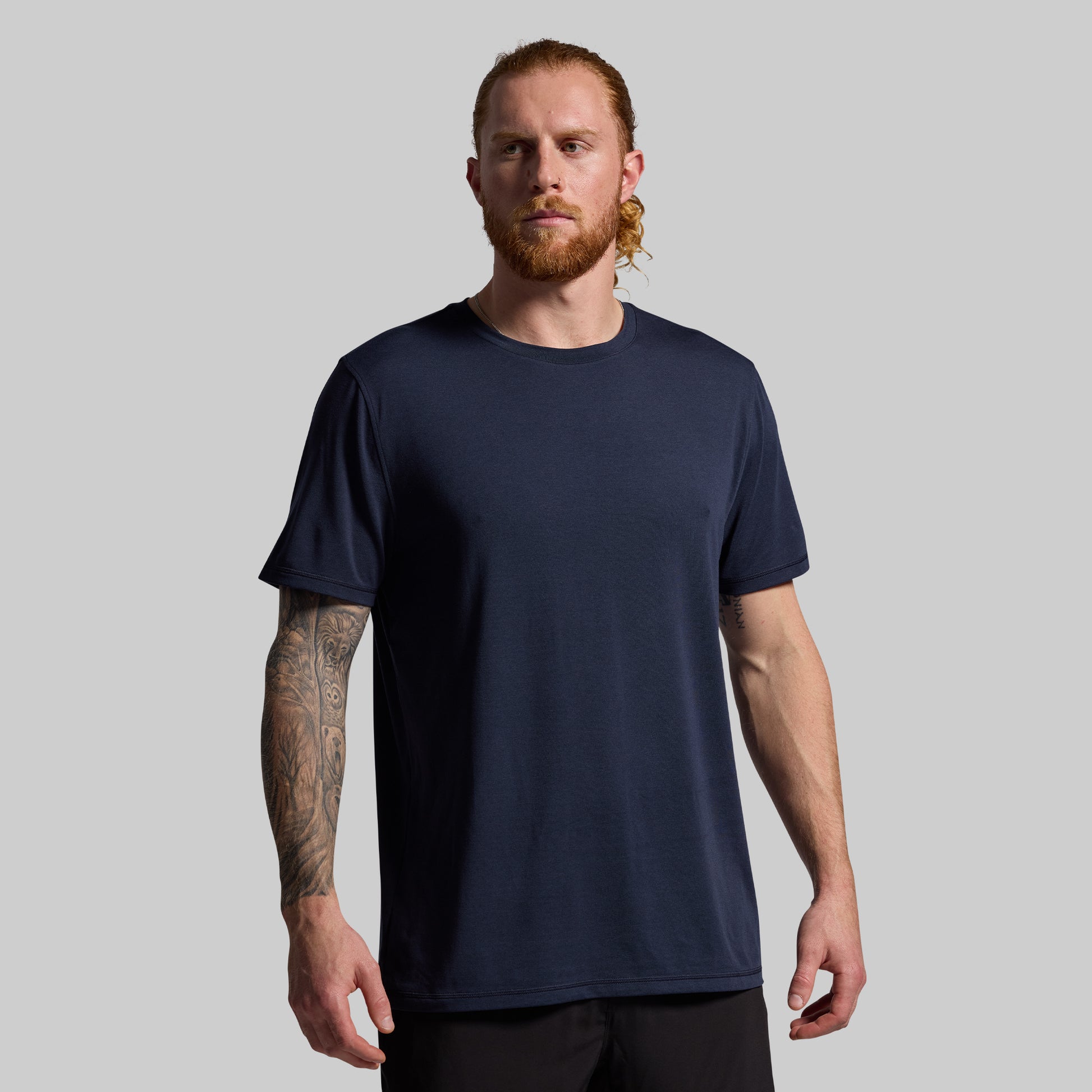 Man wearing a navy blue t-shirt against a gray background