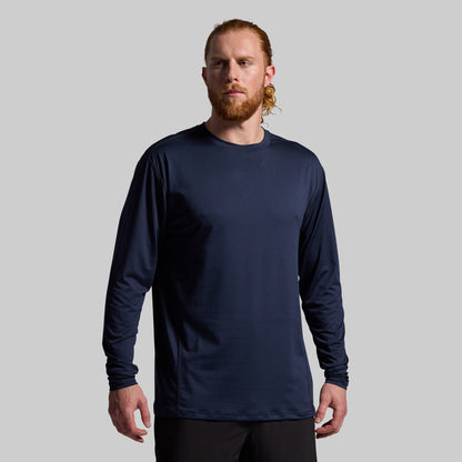 Man wearing a navy long-sleeve shirt against a gray background
