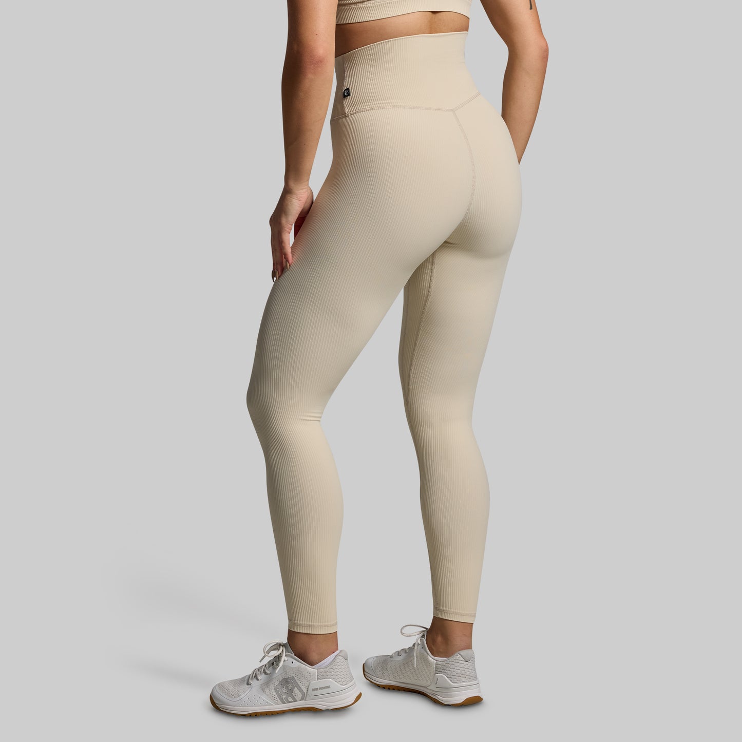 Person wearing beige leggings on a plain background