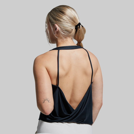 Woman wearing a black strappy top with a plain background