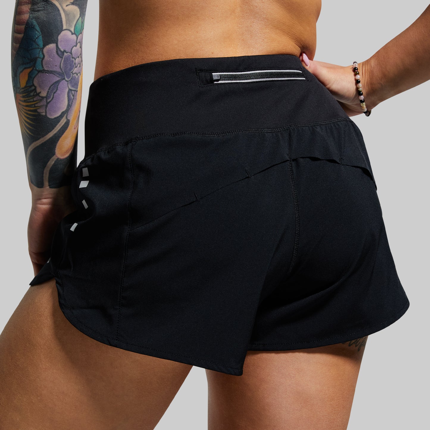 Person wearing black athletic shorts on a plain background