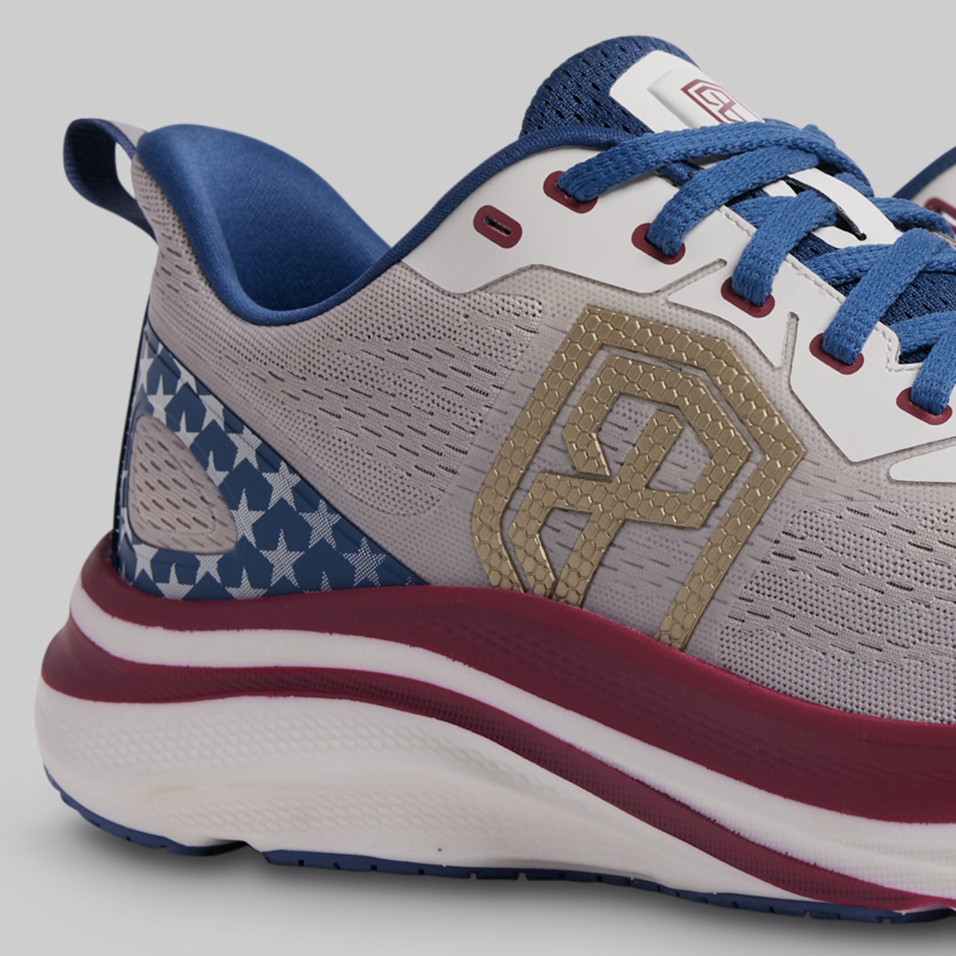 Gray athletic shoe with blue and red accents on a gray background