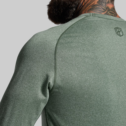 Person wearing a green athletic shirt with a brand logo on a gray background