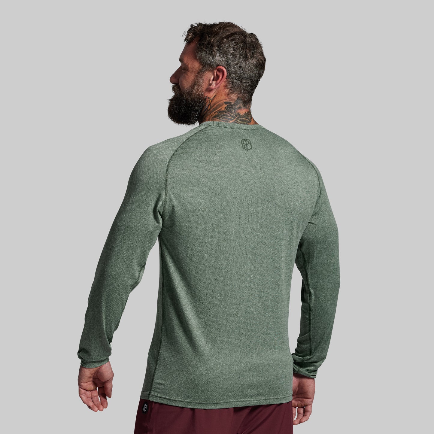 Man wearing a green long-sleeve shirt on a gray background