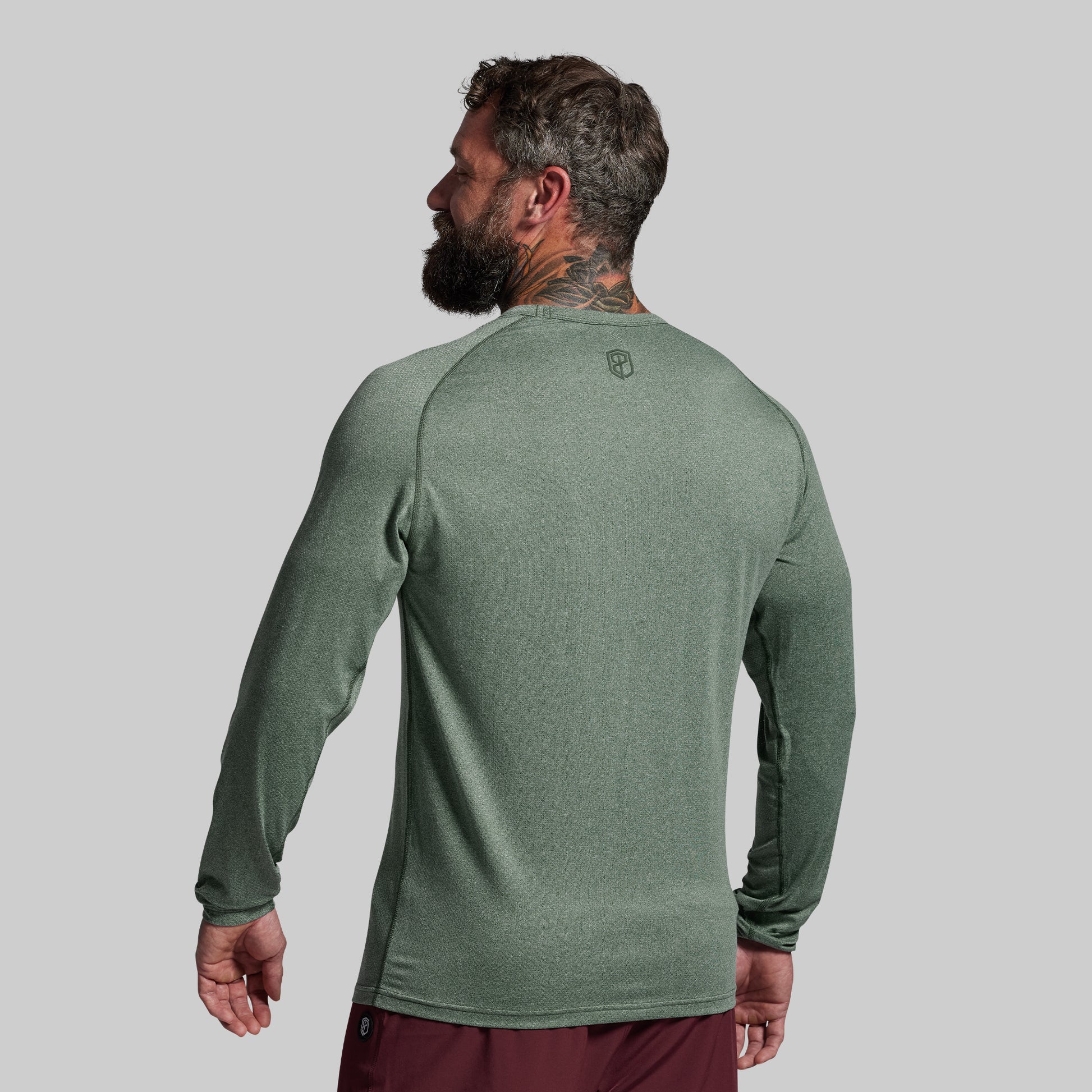 Man wearing a green long-sleeve shirt on a gray background