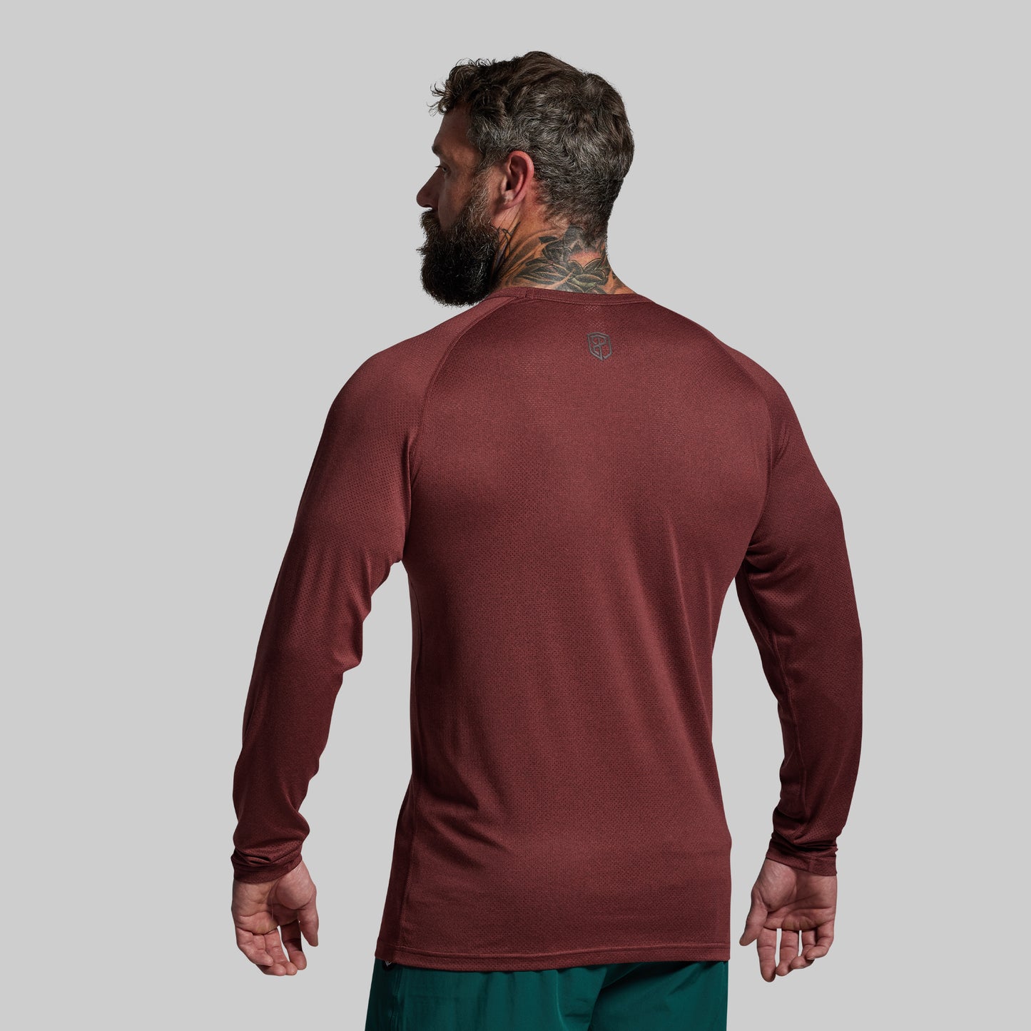 Man wearing a maroon long-sleeve shirt on a gray background