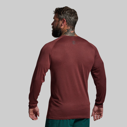 Man wearing a maroon long-sleeve shirt on a gray background