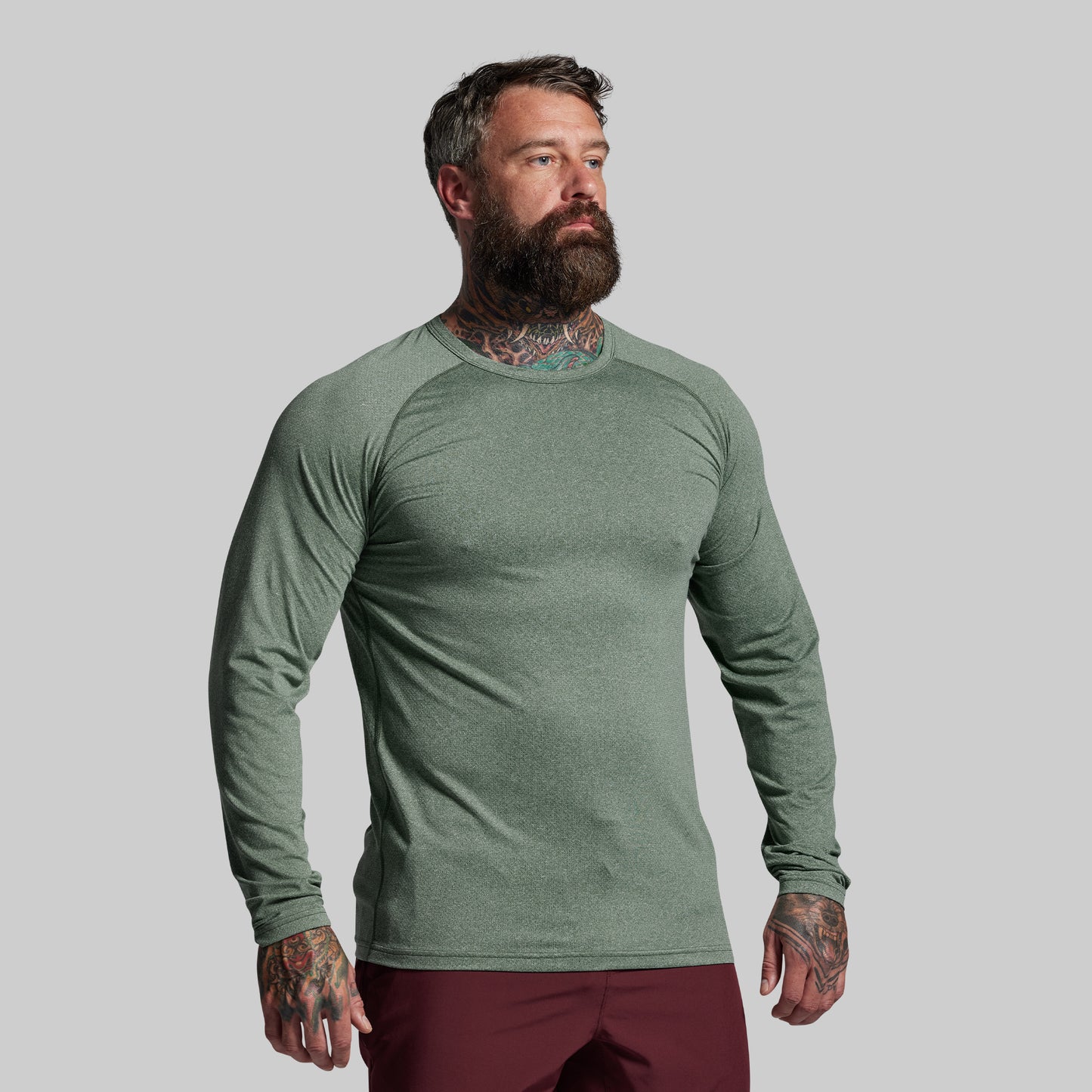Man wearing a green long-sleeve shirt against a gray background