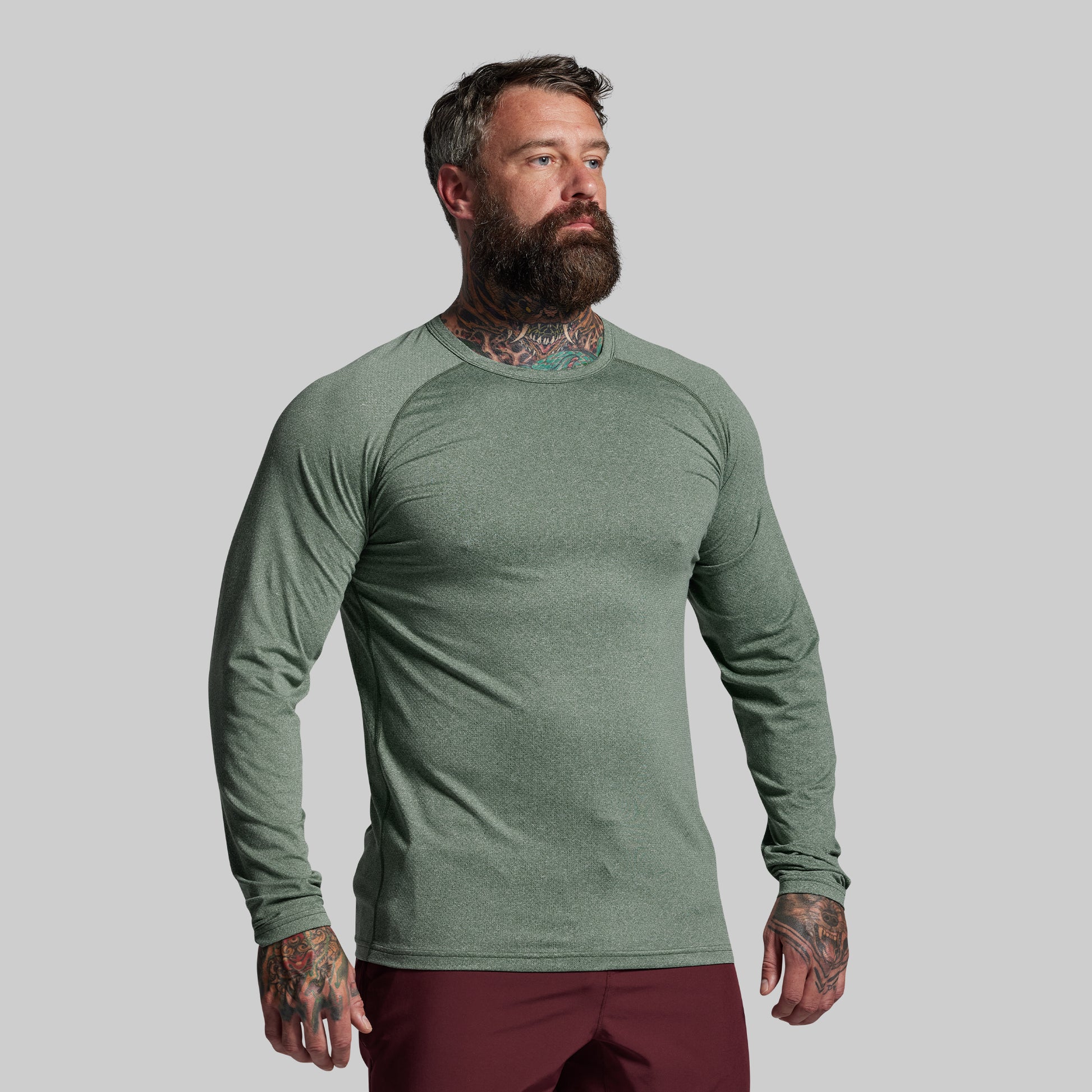 Man wearing a green long-sleeve shirt against a gray background